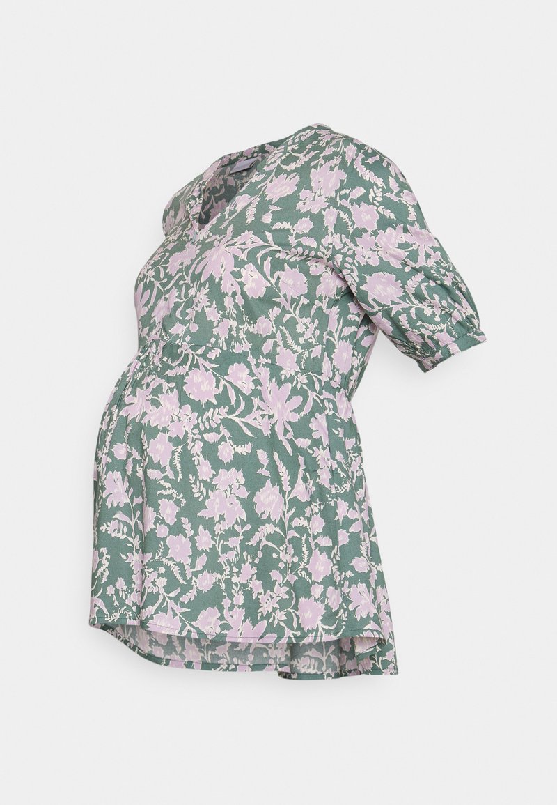 Blusa de maternidade em tecido verde com um padrão floral em rosa. Tem mangas curtas volumosas e um corte solto, ideal para uma barriga em crescimento.