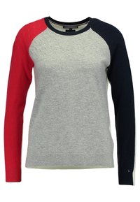 Pull avec corps texturé gris clair, manche gauche rouge, manche droite bleu marine et col rond bleu marine.