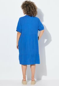 Abito blu fino al ginocchio con maniche corte a sbuffo, tessuto strutturato e orlo a strati. Presenta un colletto rotondo e cuciture sottili.