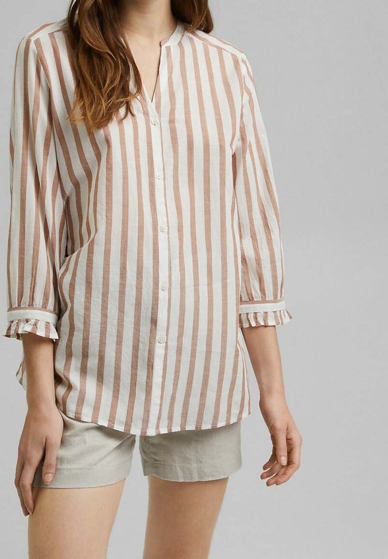 Chemise à rayures couleur crème et marron clair, avec des manches trois-quarts et des poignets volantés. Tissu léger, coupe décontractée.