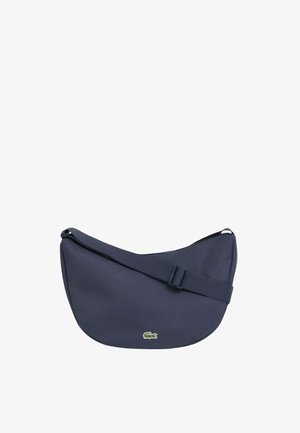 Bolso de hombro azul marino con forma de media luna, con correa ajustable y pequeño logotipo de cocodrilo verde en el centro delantero.