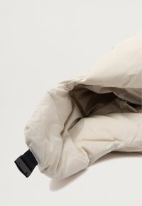 Giacca imbottita color crema con una texture liscia, dotata di una cintura nera regolabile al colletto. Il colore interno è più scuro, creando un contrasto.