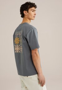 Gray cotton t-shirt featuring a graphic design with colorful flowers on the back. Short sleeves, crew neck, relaxed fit.