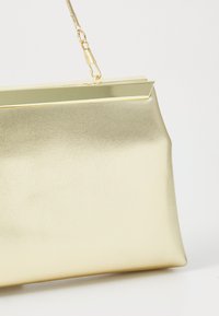 Goldfarbene metallische Clutch mit glatter Textur, rechteckiger Form und einem starren Rahmen. Sie verfügt über einen magnetischen Verschluss und einen abnehmbaren Kettenriemen.