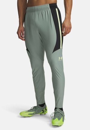 Light green athletic pants with black side inserts and reflective yellow accents. Made from a stretchy, moisture-wicking material.