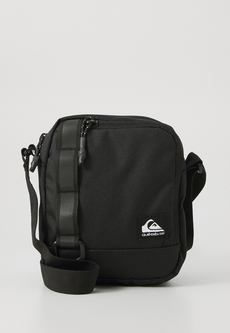 Kompaktne musta värvi ristedetail ning reguleeritava rihmaga, ees olev tõmblukk-tasku ja väike valge Quiksilveri logo patch.