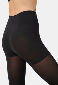 Leggings noires taille haute en tissu extensible, avec une texture lisse et un léger brillant, offrant une coupe ajustée et sans coutures visibles.