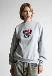 Felpa grigia decorata con un prominente logo di scorpione ricamato in rosso e nero. Presenta polsini e bordo a coste, con una vestibilità rilassata.