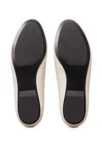 Zapatos de cuero blanco con una parte superior lisa y suelas de goma negras. Las suelas cuentan con una textura antideslizante y una sutil marca en el lateral.