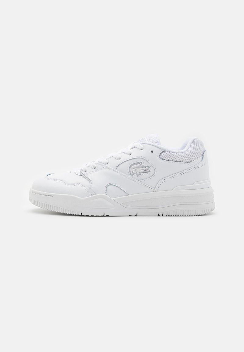 Baskets basses en cuir blanc avec lacets, logo crocodile embossé, col rembourré et semelle en caoutchouc texturée sur un fond uni.