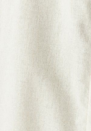 Close-up van de textuur van de stof die off-white geweven linnen toont met een licht grove weefstructuur en onregelmatigheden van natuurlijke vezels.