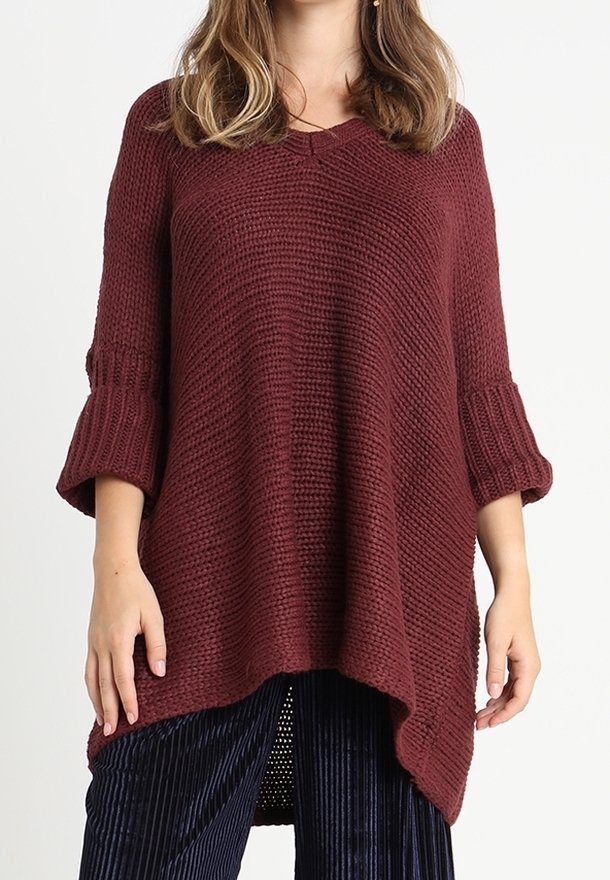 Burgundy stickad tröja med lös passform, trekvartsärmar, texturerat mönster och V-hals, kombinerad med marinblå manchesterbyxor.