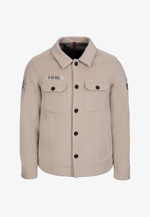 Beige jakke med knapper, to brystlommer med klap, sidelommer, sorte knapper og et 'II-UK REG.' mærke på højre bryst.
