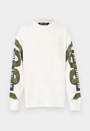 Bela bombažna majica z dolgimi rokavi z zelenim kačjim motivom, ki ovija oba rokava, ter drzno črno besedilo na desnem rokavu.