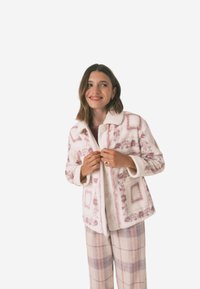 Vitt mönstrat jacka med rosa blommiga och geometriska mönster. Har krage, knappar och mjuk textur. Bärs över rutiga byxor.