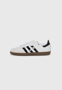 White sneaker with three black stripes, suede toe cap, and rubber sole. Features a black heel tab and gold logo detail on the side.