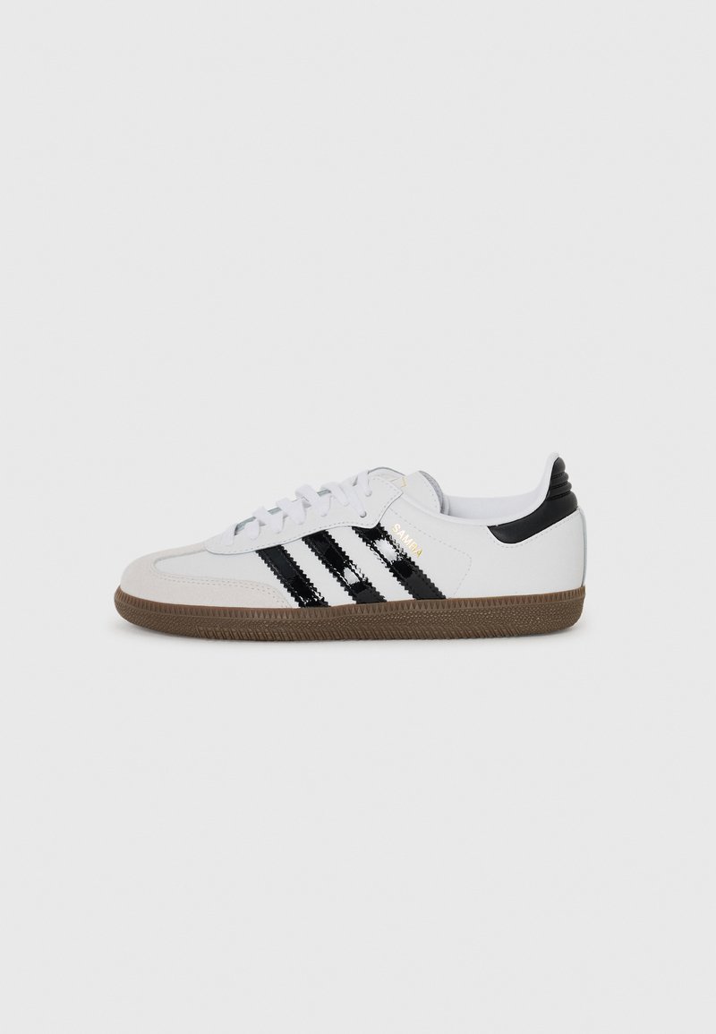 White sneaker with three black stripes, suede toe cap, and rubber sole. Features a black heel tab and gold logo detail on the side.