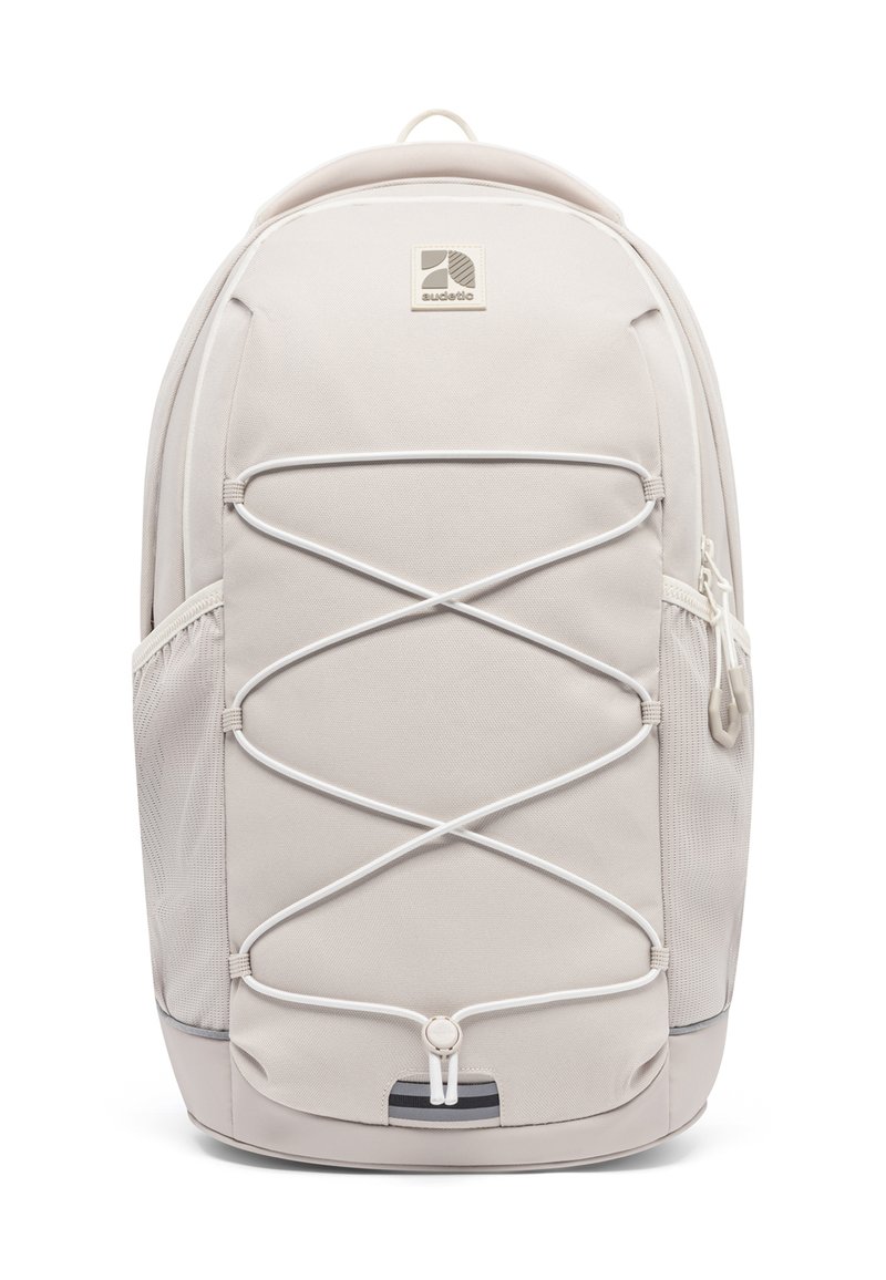 Rucsac bej cu un finisaj texturat, cu cordoane elastice bungee pe partea din față, buzunare laterale din plasă și o mâner de transport în partea de sus.