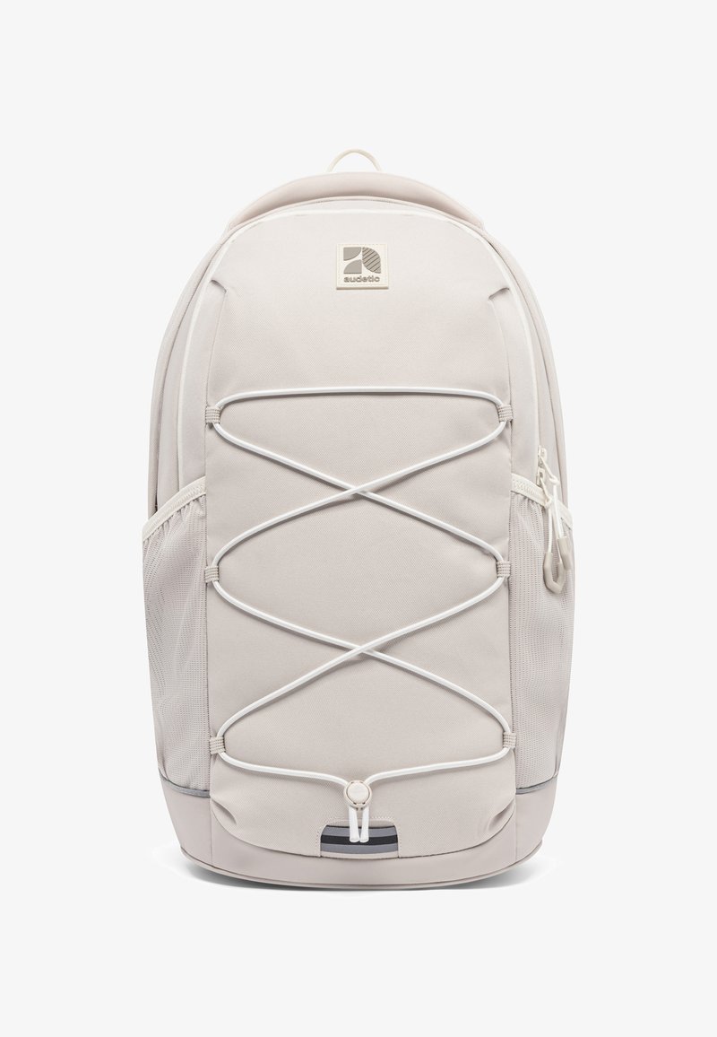 Rucsac bej cu un finisaj texturat, cu cordoane elastice bungee pe partea din față, buzunare laterale din plasă și o mâner de transport în partea de sus.