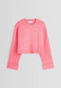 Pull court en maille rose avec manches longues à poignets et encolure ronde, posé à plat sur un fond gris clair.