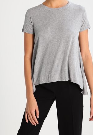 Grå T-shirt med korte ærmer i blødt stof, med en afslappet pasform, rund halsudskæring og let buet kant, kombineret med sorte bukser.