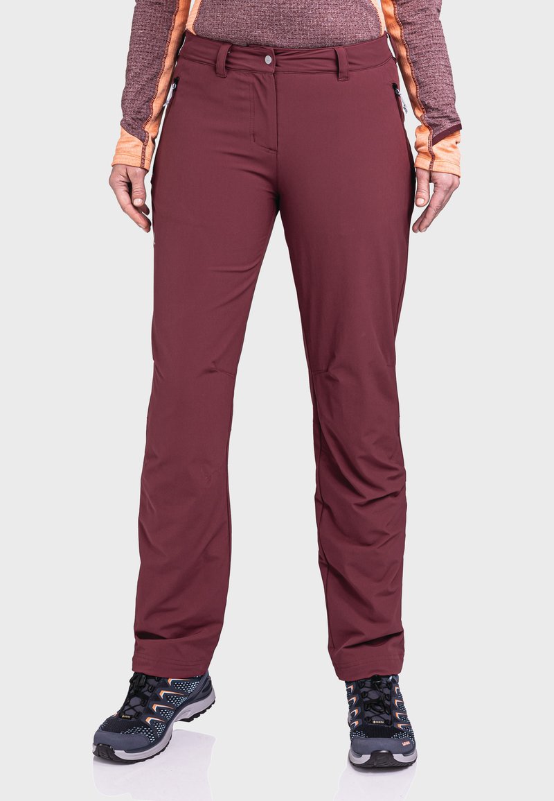 Bordeauxfarbene Softshell-Hosen mit schmaler Passform, mit seitlichen Reißverschlusstaschen und kontrastierenden Nähten, kombiniert mit schwarzen Wanderschuhen mit gemusterter Sohle.