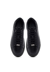 Un paio di sneakers in pelle nera con lacci neri e puntali in metallo per il logo, viste dall'alto su uno sfondo bianco.