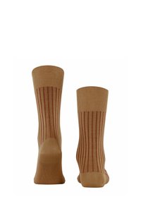 Calzini beige con texture a coste e strisce verticali rosse, mostrati dal retro per evidenziare il motivo e i dettagli del design.