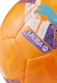 Narančasta nogometna lopta s teksturiranom površinom, koja sadrži LaLiga brending, geometrijske uzorke u ljubičastoj i akvamarinskoj boji, te istaknute šavove.