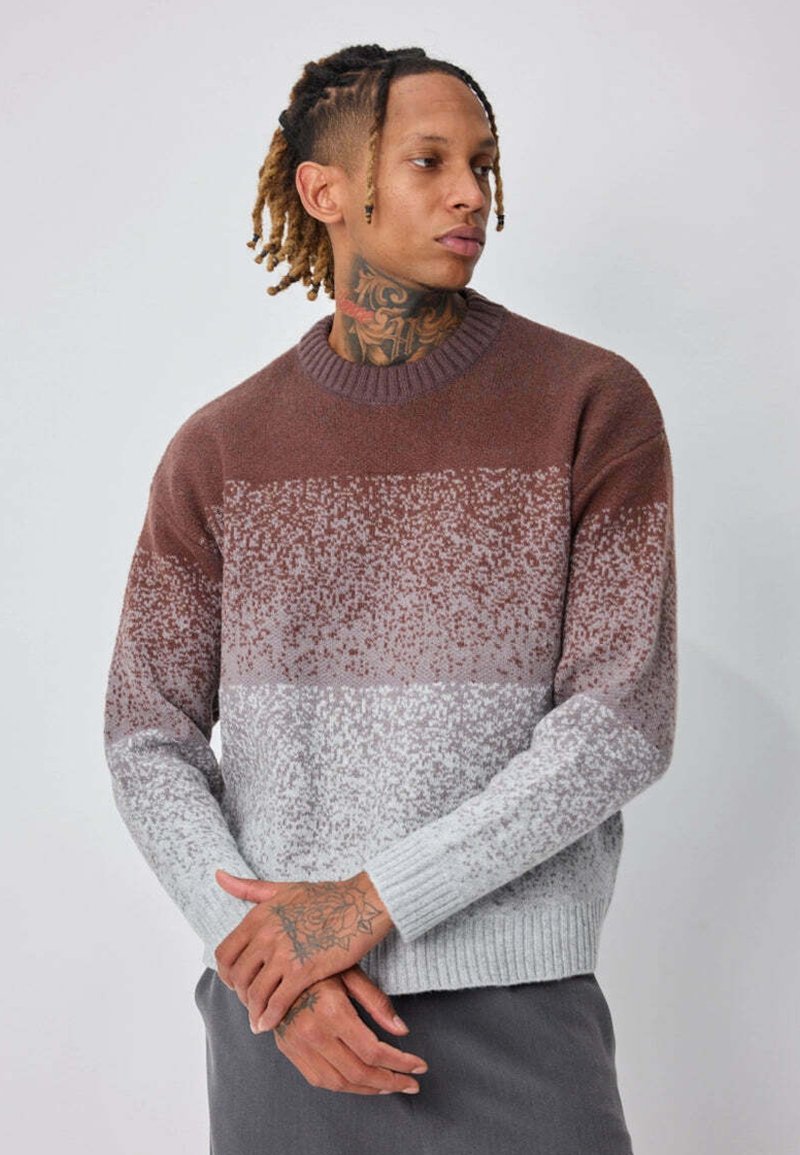 Pull en tricot présentant un dégradé de couleurs marron, gris et blanc, avec un col et des poignets côtelés, ainsi qu'un motif texturé moucheté.