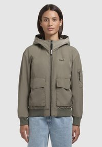 Veste bomber légère couleur vert olive avec capuche, fermeture éclair, deux poches avant et poignets côtelés. Texture lisse et design minimaliste.