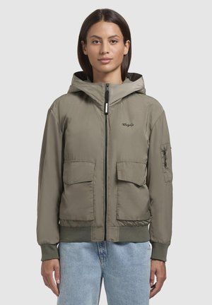Veste bomber légère couleur vert olive avec capuche, fermeture éclair, deux poches avant et poignets côtelés. Texture lisse et design minimaliste.