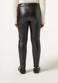 Leggings in finta pelle nera con una finitura lucida e slanciata. Banda in vita alta con un design liscio e aderente. Cuciture sulle gambe sottili.