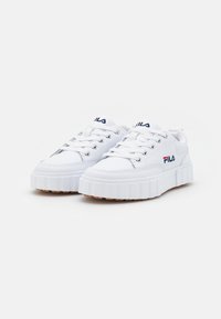 Sneakers sintetici bianchi con suola bianca spessa e fondo in gomma. Le caratteristiche includono chiusura con lacci e design sovrapposto.