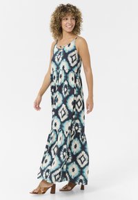Maxi obleka s tie-dye vzorcem v modri, beli in mornarski barvi. S pasom, večplastna silhueta in lepega roba. Ujemajoča se s rjavimi petami.