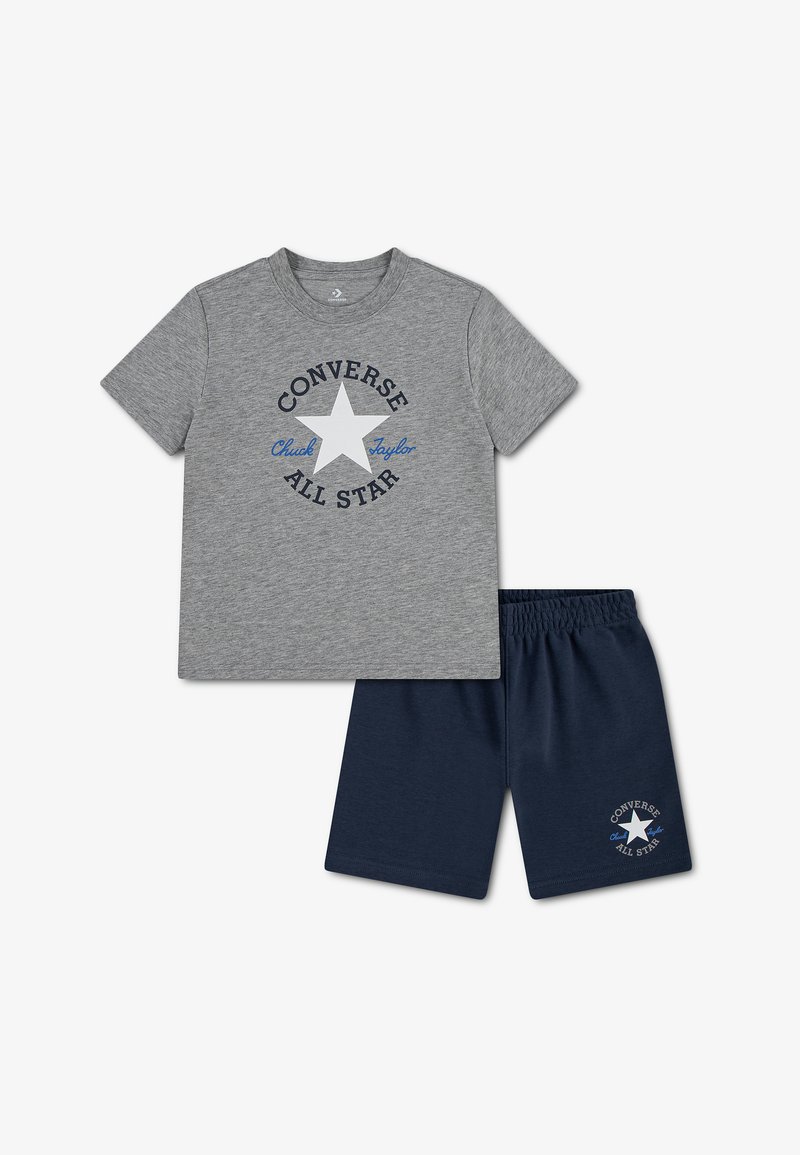 T-shirt gris à manches courtes Converse All Star avec étoile blanche et short bleu marine affichant le même logo sur la jambe gauche.