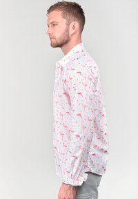 Heren wit shirt met een patroon van roze flamingo's, met een button-down kraag, lange mouwen en elastische manchetten, gemaakt van lichtgewicht stof.