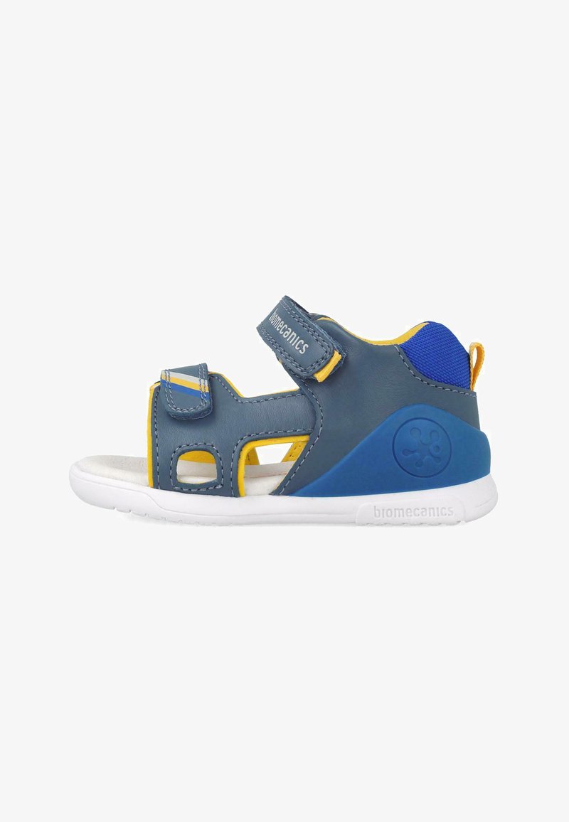 Sandal azul y amarillo con parte superior sintética, correas de velcro, cortes para transpirabilidad y suela de goma blanca. Logo de la marca en el lateral.