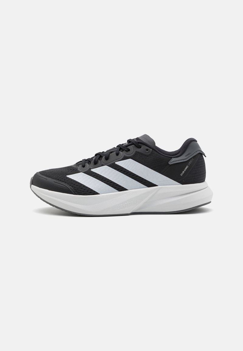 Chaussures de sport noires avec une tige en mesh respirant, trois rayures blanches et une semelle intermédiaire gris clair avec le logo "LIGHTSTRIKE".