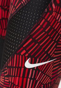 Męskie legginsy sportowe w kolorze czarnym i czerwonym. Posiadają geometryczne wzory oraz otwory wentylacyjne z kontrastującymi szwami. Widoczne białe logo.