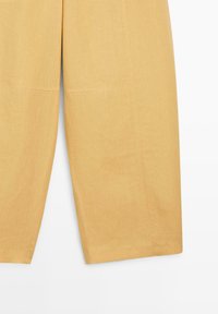 Pantalon jaune à jambes larges avec coutures visibles et ourlet droit, présenté sur fond blanc.