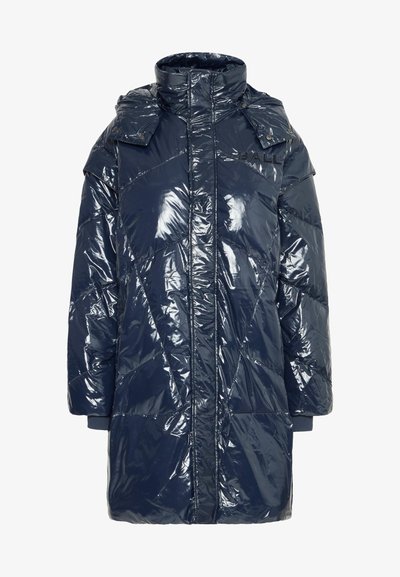 Mornarsko modra, sijoča pufasta jakna z visokim ovratnikom in gumbi s sponkami. Prešita zasnova in rebrasti manšeti za dodatno toploto.