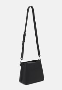 Zwarte synthetische schoudertas met een gestructureerde afwerking, verstelbare schouderband en een ritssluiting hoofdvak. Minimalistisch ontwerp, zacht afgeronde vorm.