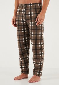 Pantalons de pyjama à carreaux marron en polaire douce, présentant un motif à damiers avec des accents blancs et noirs, et une taille élastique.