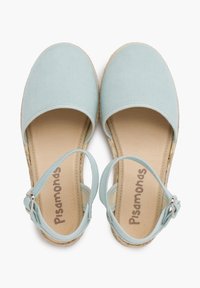 Espadrilles en tissu bleu clair avec un bout arrondi, une bride autour de la cheville et une semelle tissée. Nom de la marque "Pisamonas" imprimé sur la semelle intérieure.