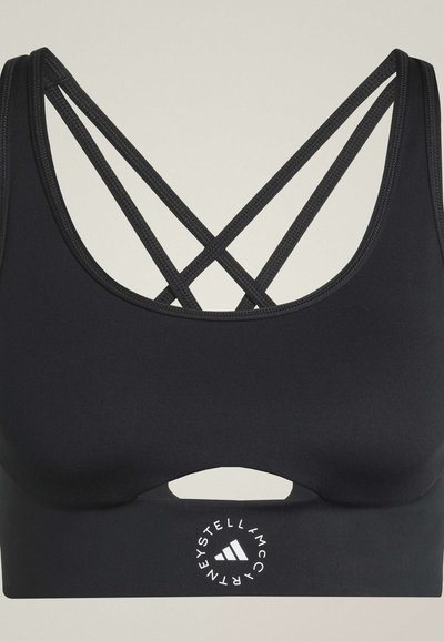 Reggiseno sportivo nero con sottili spalline incrociate e un piccolo logo circolare con testo al centro in basso.