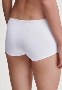 Witte naadloze hipster shorts gemaakt van glad, rekbaar materiaal, met een lage tailleband en een minimalistisch ontwerp.