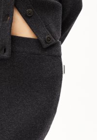 Ciemnoszary sweter dziany o prążkowanej fakturze, z czarnymi guzikami i wycięciem. Dopasowany do ciemnoszarego paska spódnicy o identycznym kolorze.