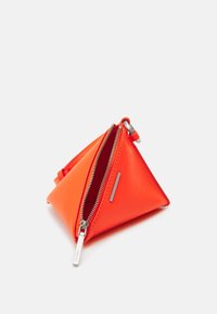 Pañuelo triangular naranja hecho de material sintético suave. Presenta dos cremalleras plateadas y una pequeña etiqueta metálica en un lado.