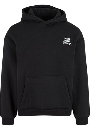 Zwarte hoodie gemaakt van zachte katoen, met een voorzak en witte tekst "own your story" op de linkerborst.
